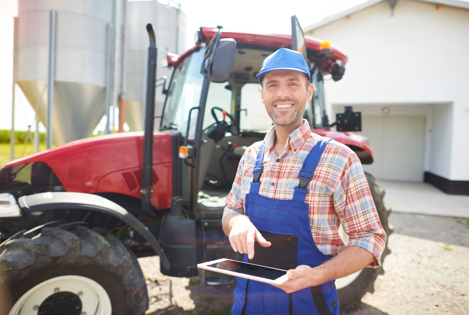 Un homme en cote, mécanicien agricole, pose devant un tracteur