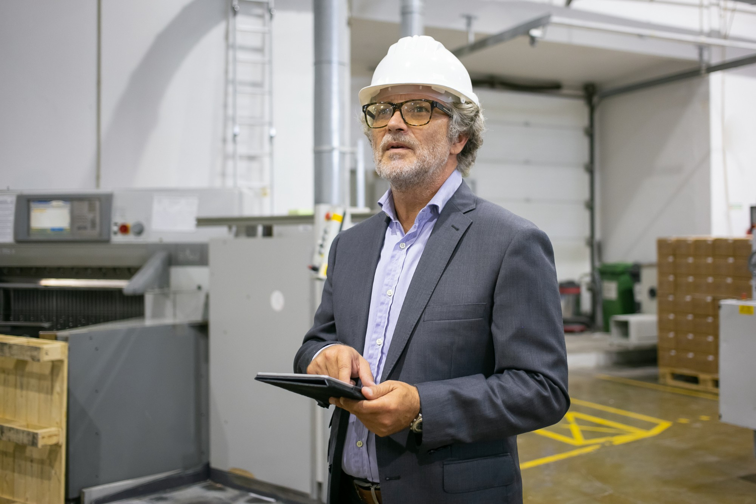 Un homme avec un casque réfléchit dans une usine